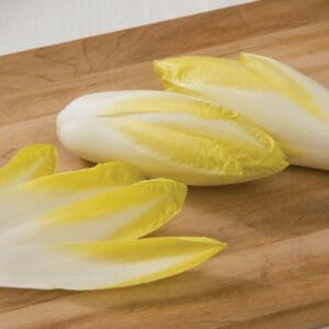 Fresh Belgian endives on a wooden cutting board.