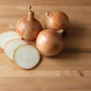 Whole and sliced onions on a wooden surface.