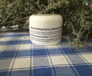 A small white jar of hemp healing salve on a blue checkered cloth.