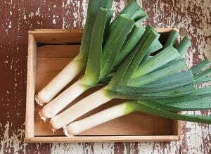 Fresh leeks neatly arranged in a wooden crate.