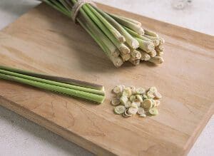 Fresh lemongrass stalks whole and sliced on a wooden cutting board.