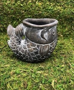 A gray fish-shaped planter with detailed scales sits on grass.
