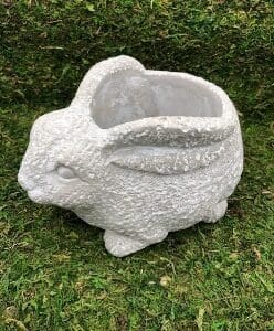 White ceramic planter shaped like a rabbit on grass.