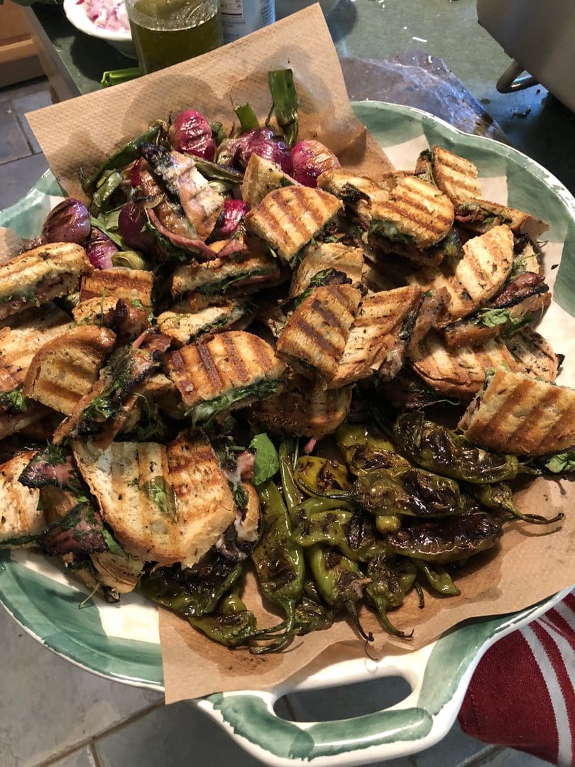 Grilled chicken pieces served with roasted green chili peppers on a plate.