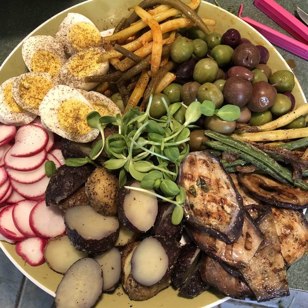 A colorful plate with grilled chicken, veggies, eggs, and fries.