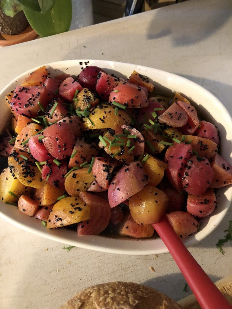Colorful roasted vegetables with herbs in a white dish.
