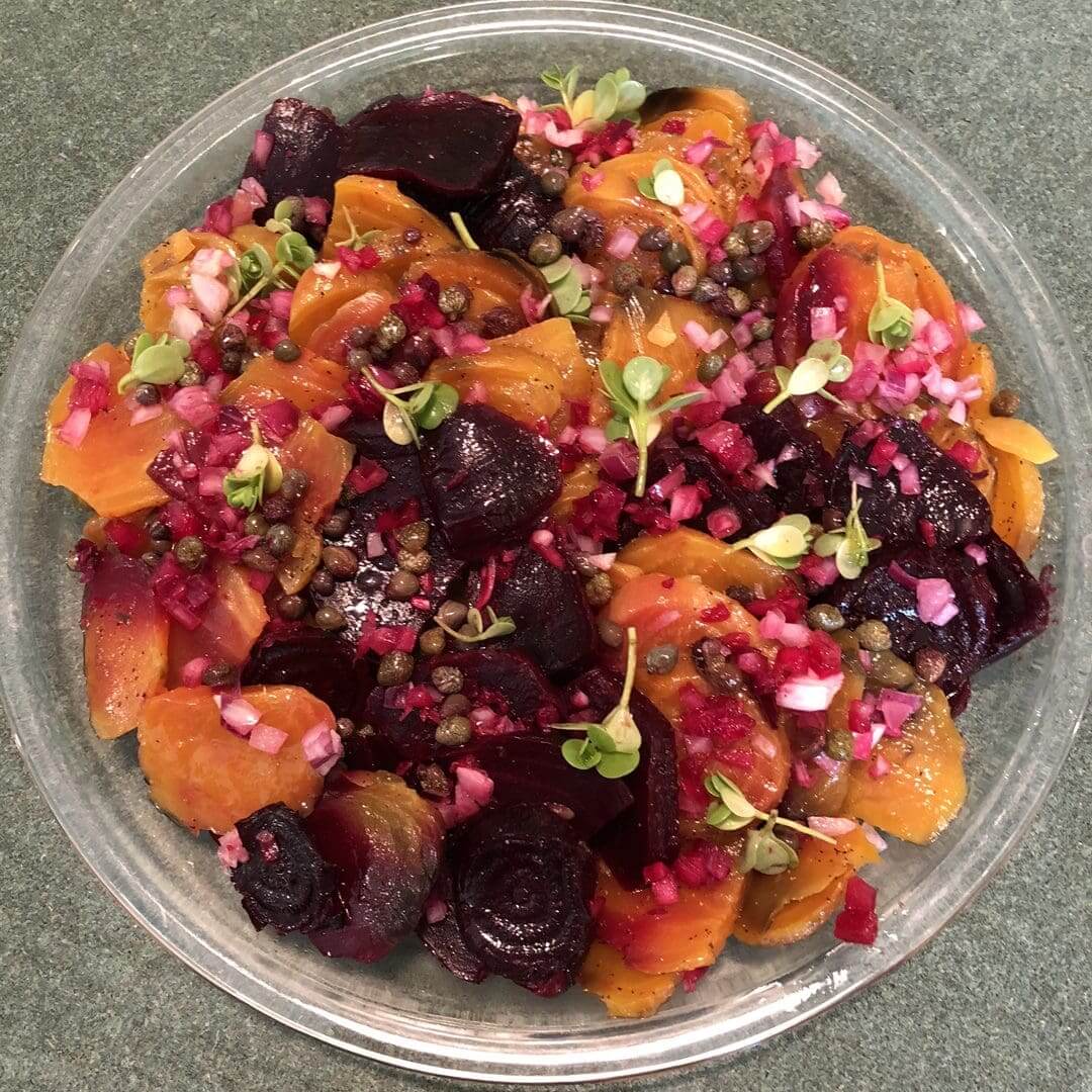 Colorful beet and orange salad in a clear bowl.