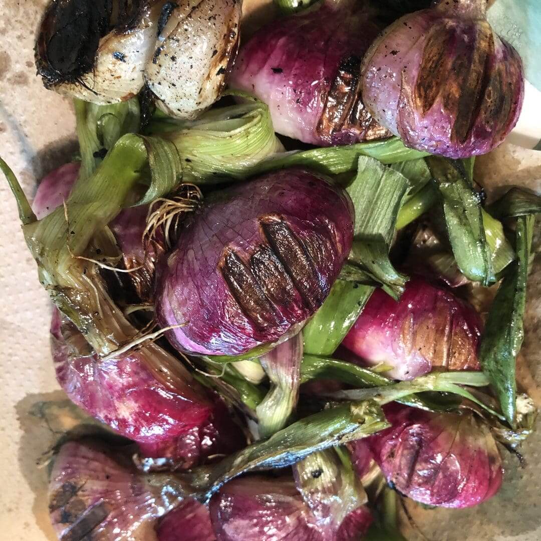 Freshly harvested purple garlic bulbs with green stems.