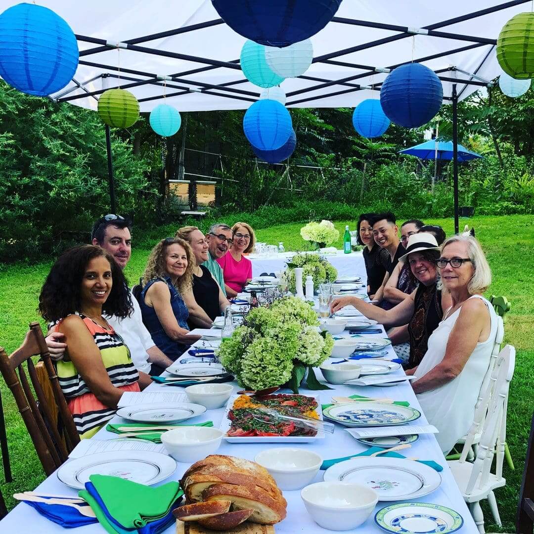 Friends gathered around a long outdoor dining table decorated with blue and green accents.