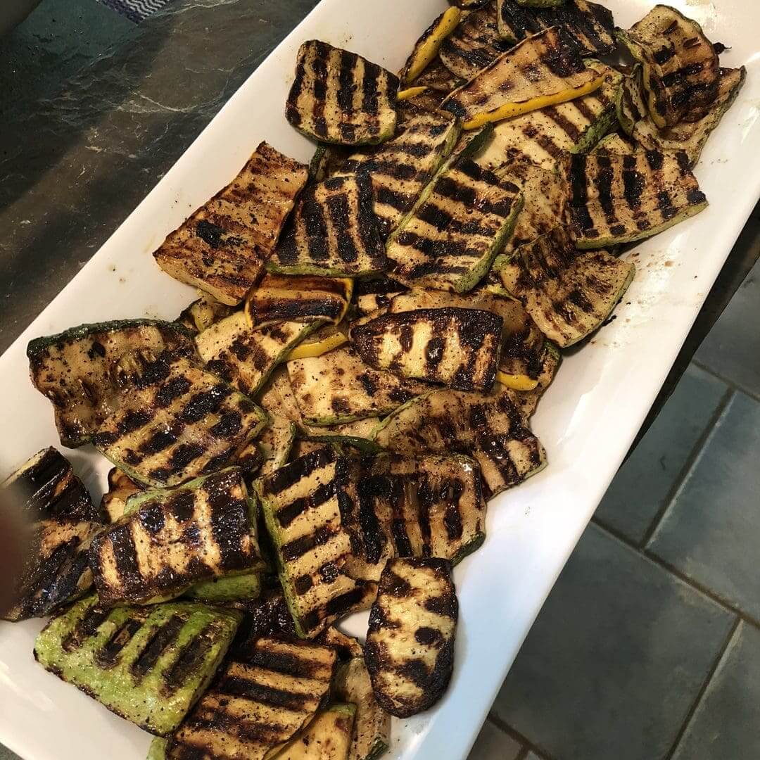 Grilled zucchini slices with char marks on a white platter.