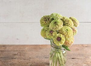 A bouquet of pale green and yellow flowers tied with twine on a wooden surface.