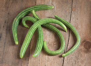 Fresh green ridge gourds arranged on a wooden surface.