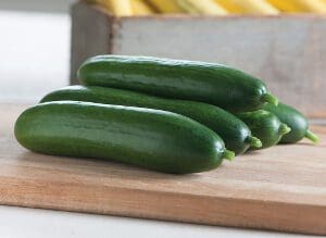 Fresh zucchinis neatly arranged on a wooden cutting board.