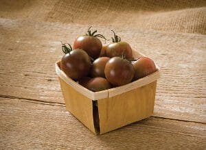 Basket of ripe tomatoes on a rustic wooden surface.
