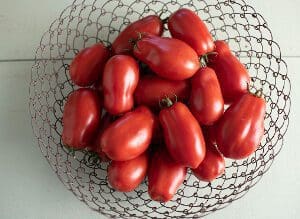 A bowl filled with fresh red plum tomatoes.