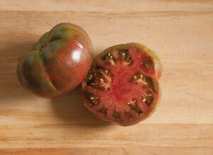 Two ripe heirloom tomatoes on a wooden surface.
