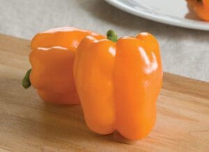 A fresh orange bell pepper on a wooden surface.