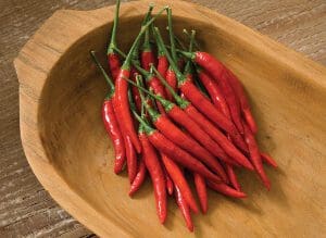 A bunch of fresh red chili peppers in a wooden bowl.