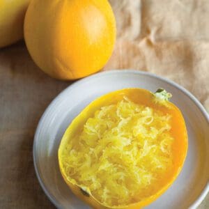 A spoonful of bright yellow shredded mango on a white plate.