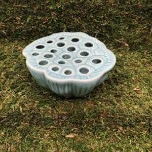 Blue ceramic flower frog on green grass