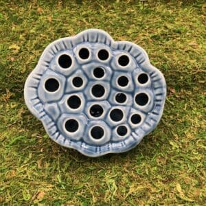 Blue ceramic flower frog on grass